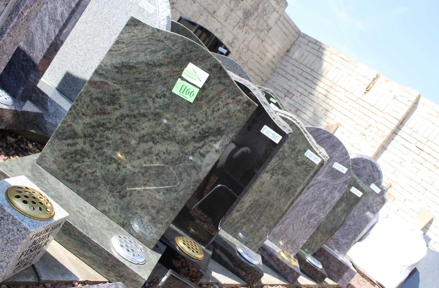 Row of granite headstones in different colours at the display yard, including tropical green